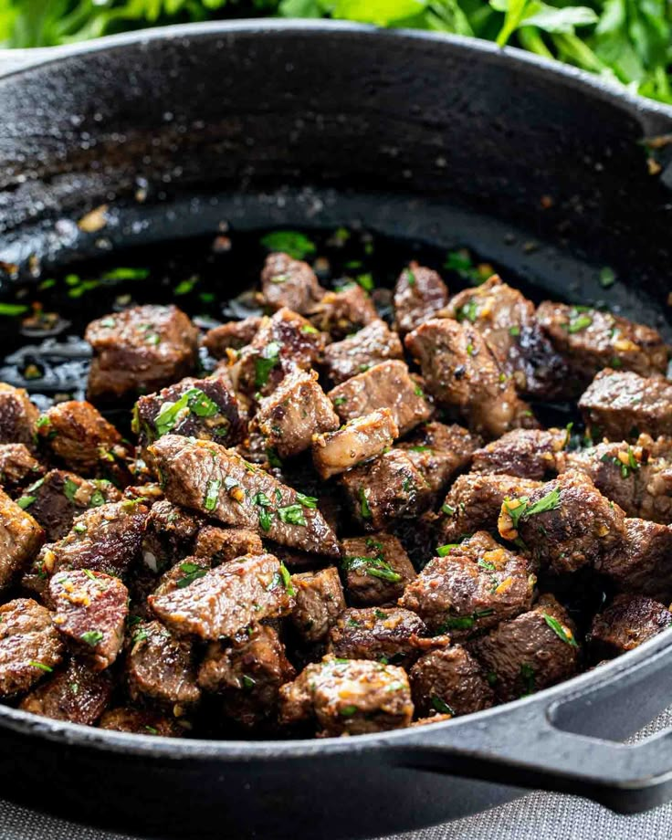 a skillet filled with meat and garnished with parsley on the side