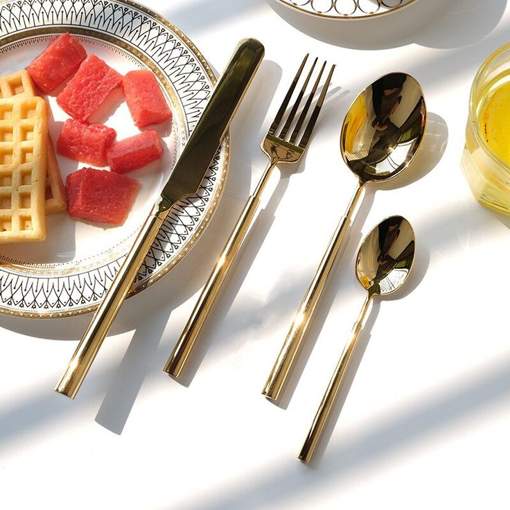 a plate with waffles, watermelon slices and goldware on it