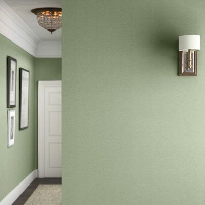 a green wall with two pictures on it and a light fixture hanging from the ceiling