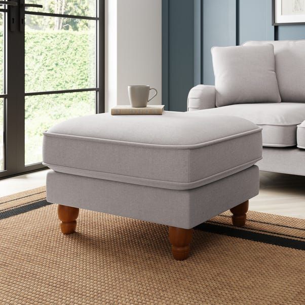 a white ottoman sitting on top of a rug in a living room