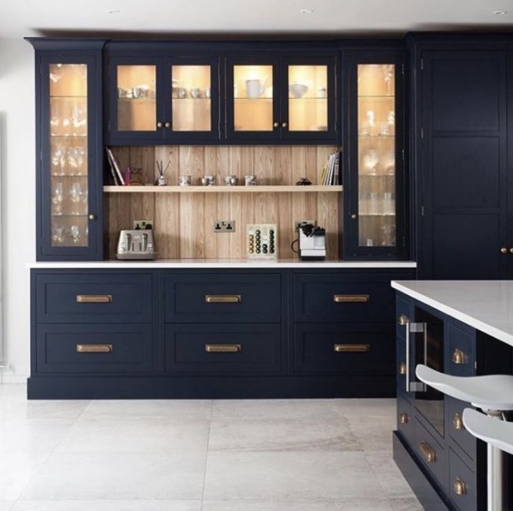 a kitchen with dark blue cabinets and white counter tops, gold pulls on the doors