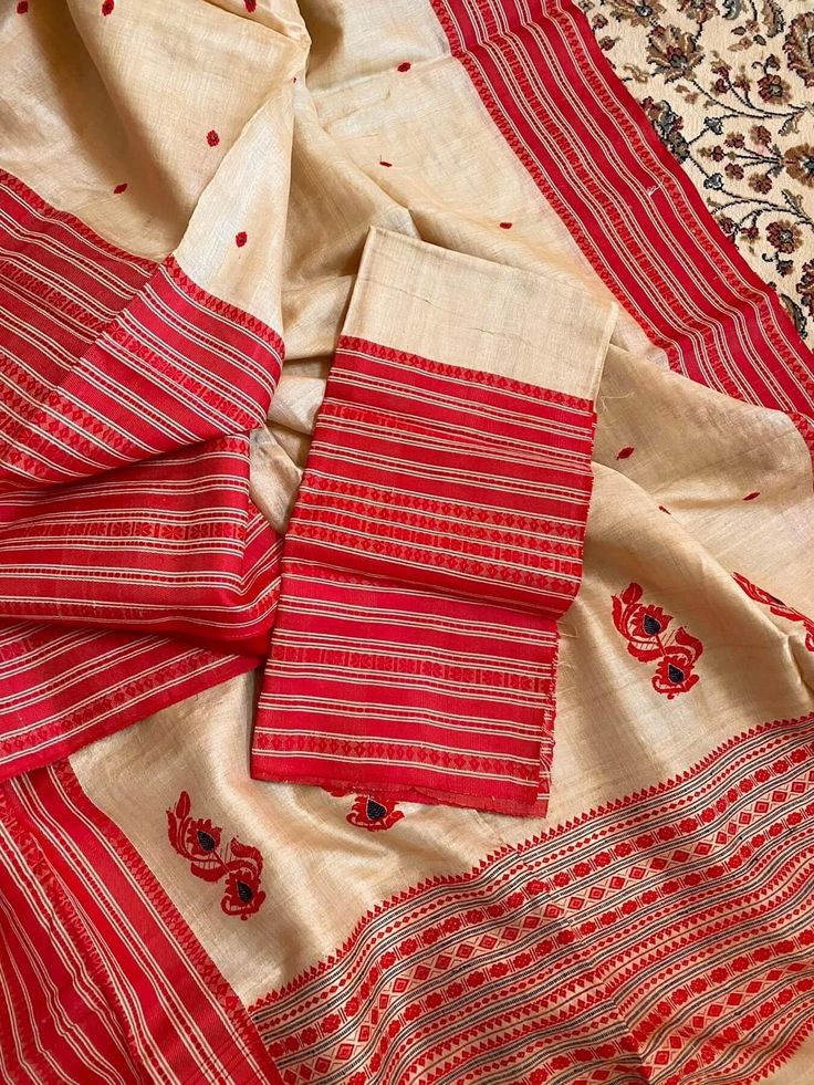 This is a creation of the master weavers of Bengal , Fulia . This saree is made of pure gachhi by gachhi  tussar and the border snd pallu is pure silk  . Very easy to carry it . One side has broad border other narrow . The colour has an  unique combinations .  Saree comes with a running blouse piece .  As it is entirely handmade so some irregularities is the mark of originality of handloom product.  With Silk mark certificate of India Government .  Fall and pico , tassel done and complimentary .  Note : Please leave your phone no and email id for shipping purpose. Motif Slub Silk Saree For Puja, Slub Silk Saree With Motifs For Puja, Navratri Katan Silk Saree With Woven Motifs, Red Slub Silk Saree With Weaving Work, Unstitched Slub Silk Saree With Woven Motifs, Traditional Katan Silk Saree With Woven Motifs, Slub Silk Traditional Wear With Weaving Work For Puja, Navratri Semi-stitched Saree With Weaving Work, Navratri Tussar Silk Saree With Woven Motifs