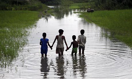 three children holding hands walking through water