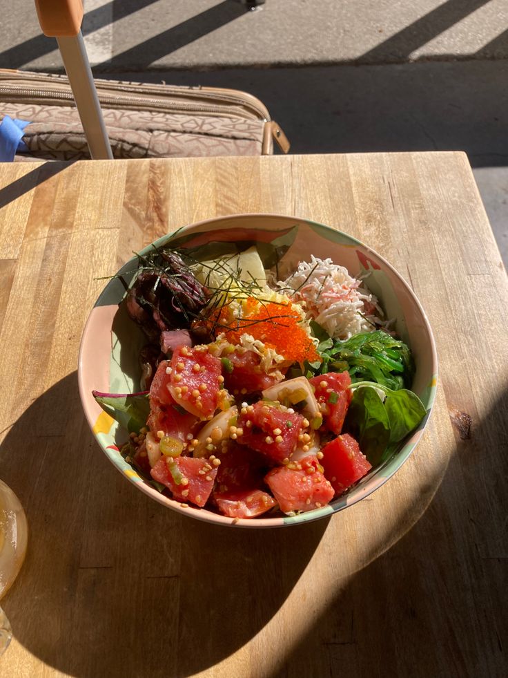 a wooden table topped with a bowl of salad