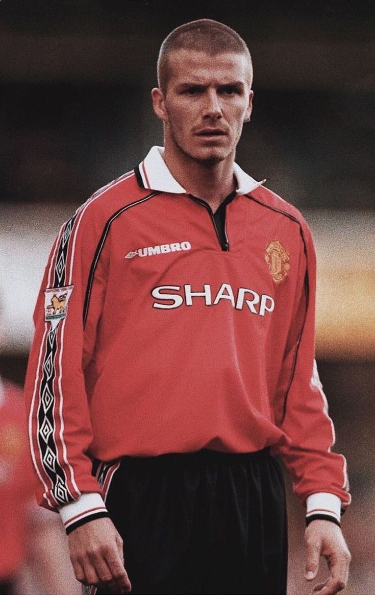 a man standing on top of a soccer field wearing a red shirt and black shorts