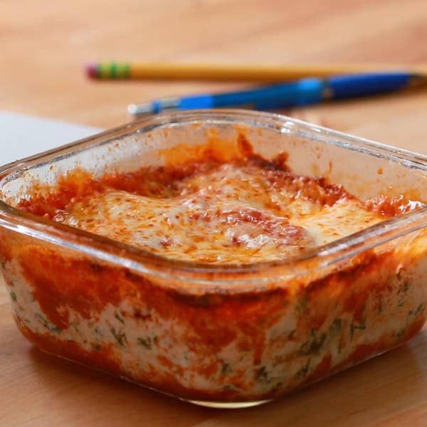 a casserole dish on a wooden table with two colored pencils