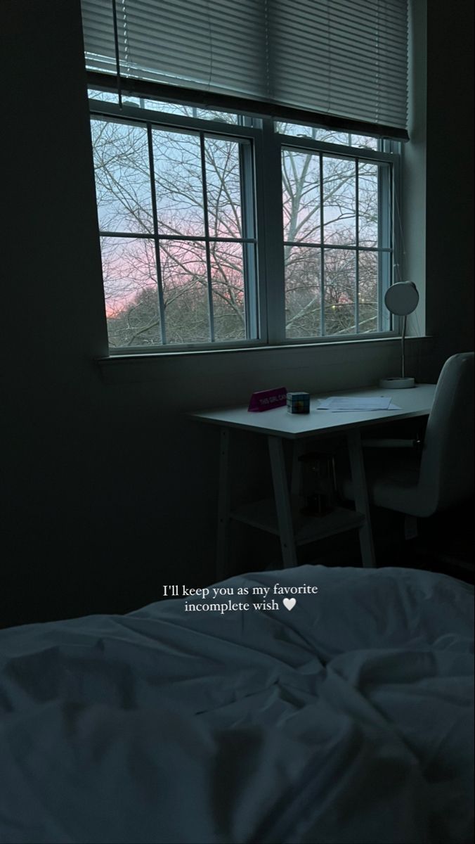 a bed sitting under a window next to a desk