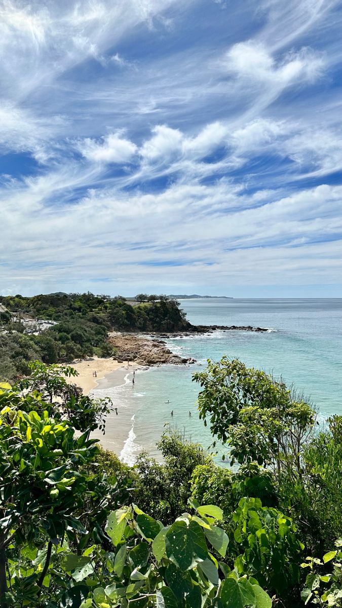 the beach is surrounded by lush green trees and blue skies with white clouds in the background