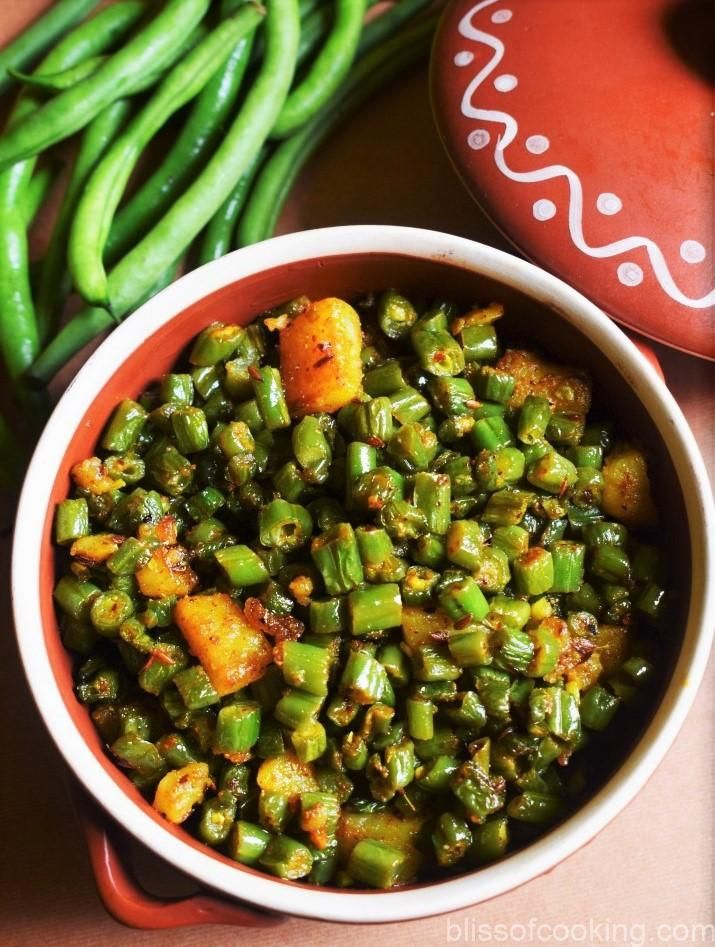 green beans and carrots in a bowl next to a red vase with writing on it