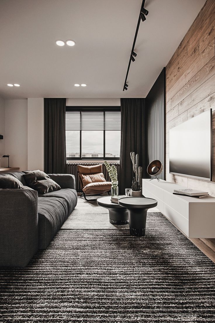 a living room with couches, tables and a flat screen tv on the wall