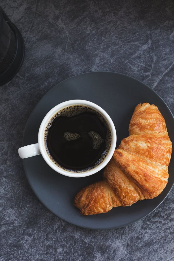 there is a croissant and coffee on the plate