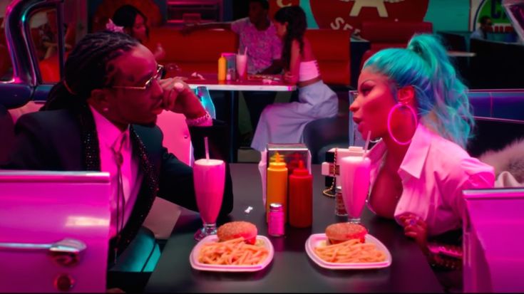 two people sitting at a table with food and drinks