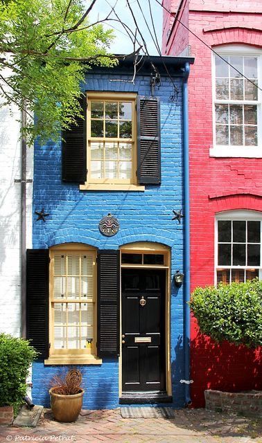 two houses with black shutters and red brick walls, one has a blue door