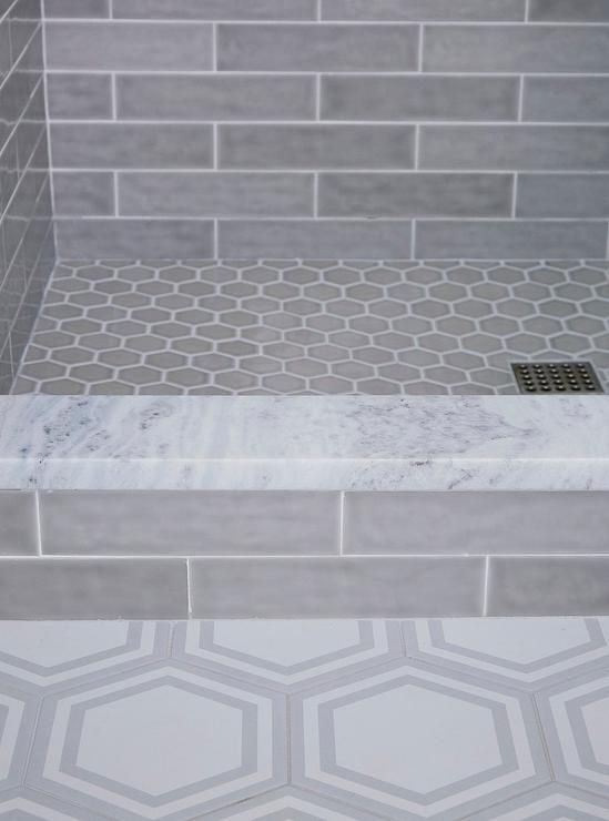 a bathroom with grey tile and white hexagonal tiles