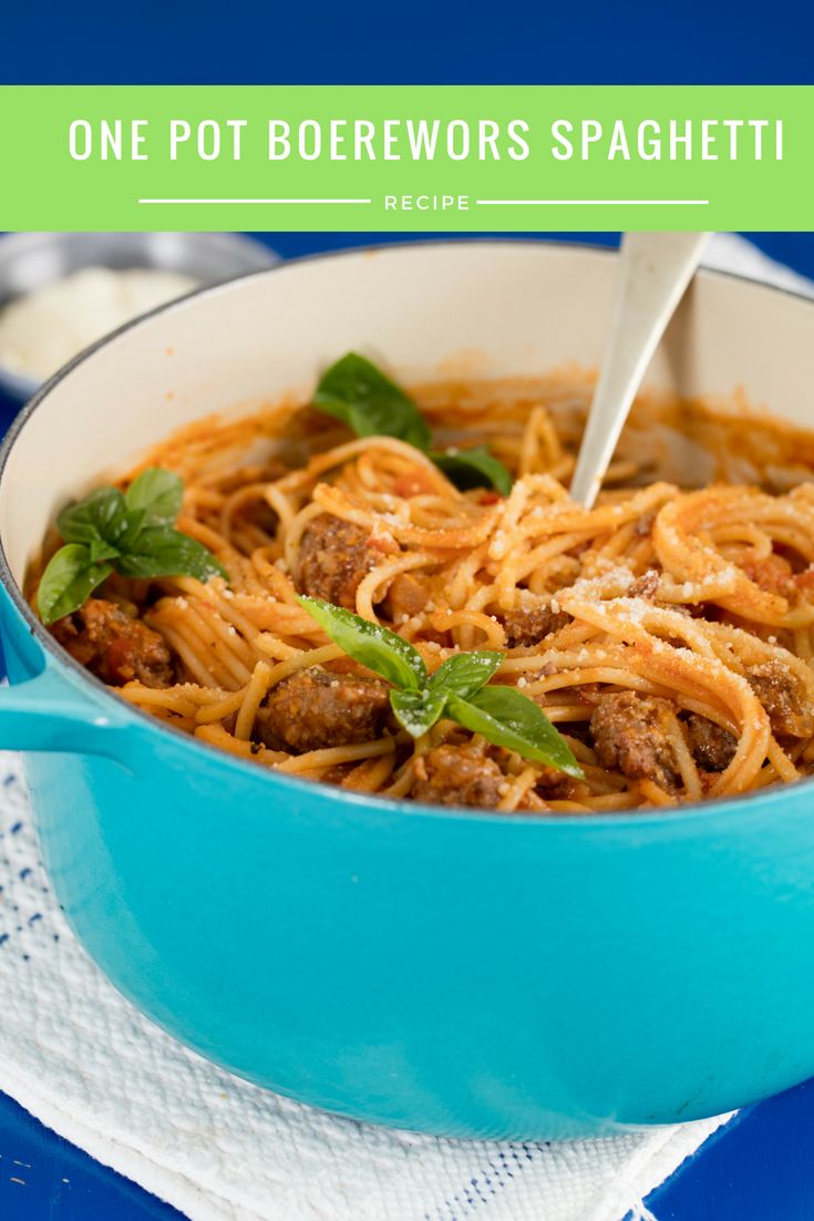 a blue pot filled with spaghetti and meat on top of a white cloth next to a fork