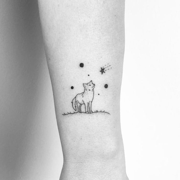 a small tattoo on the ankle of a person with a cat and stars in the sky