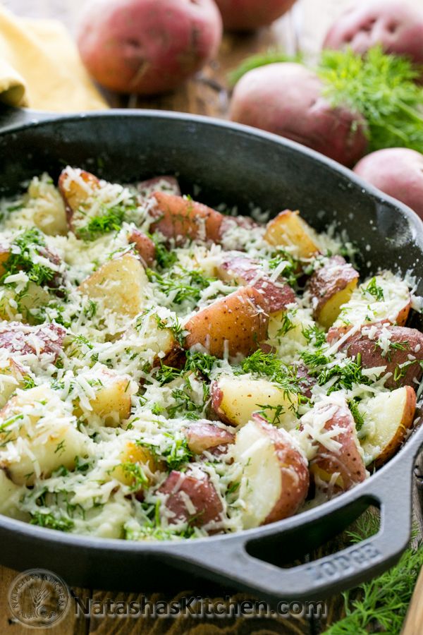 a pan filled with potatoes and broccoli on top of a wooden cutting board