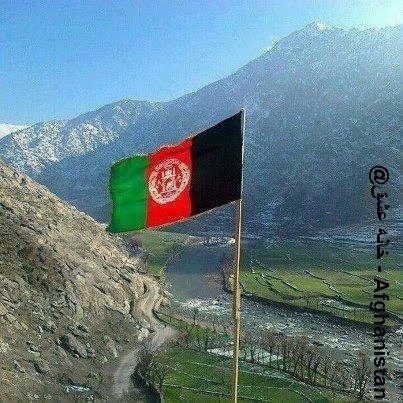 an afghan flag flying on top of a mountain