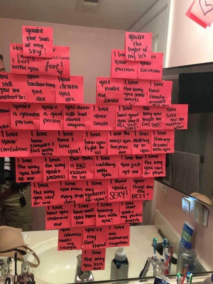 a bathroom sink with pink sticky notes attached to the wall and a mirror in front of it