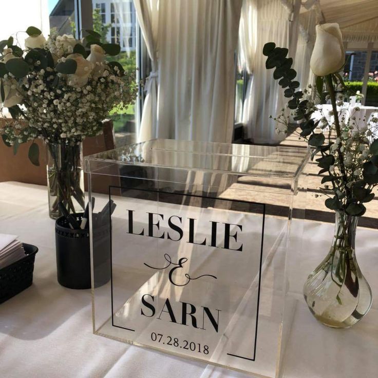 two vases with flowers are sitting on a table in front of a sign that says leslie and sarn