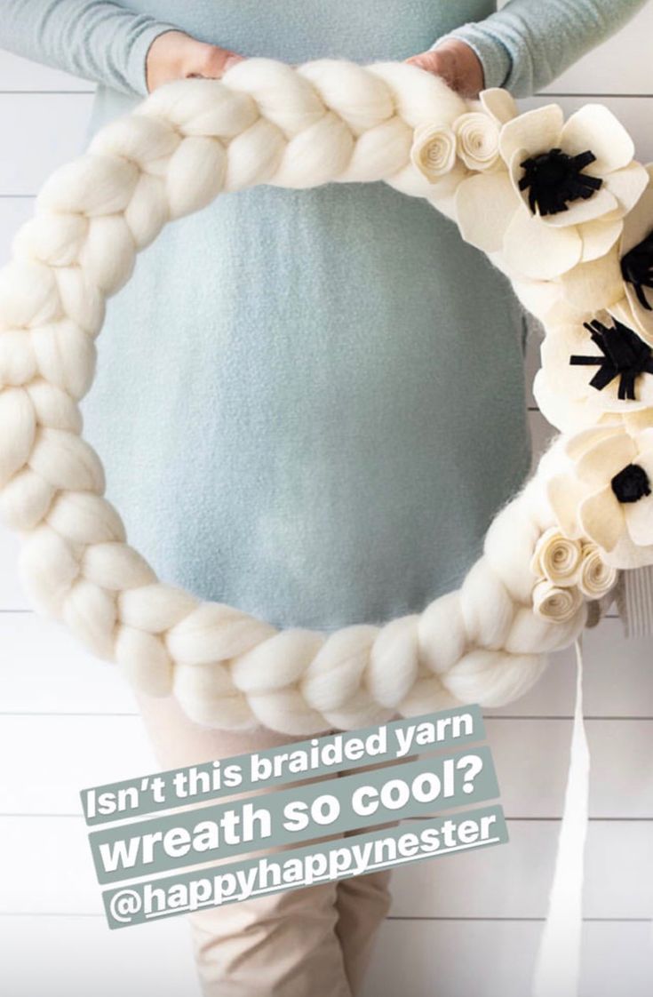 a woman is holding a wreath made out of yarn with flowers on it and the words, isn't this braided yarn wreath wreath so cool?