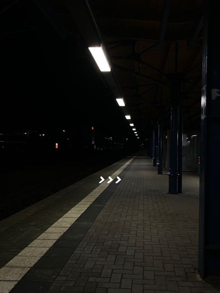 an empty train station at night with no people on the platform or in the dark