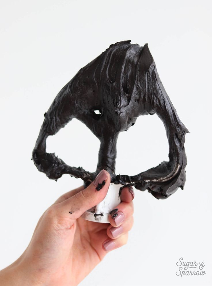 a person holding up a fake animal head made out of dark chocolate and black icing