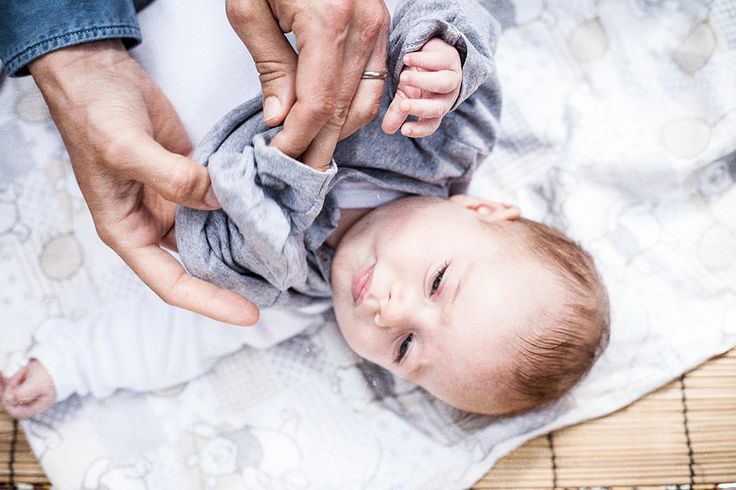 a baby laying on its back being held by an adult's hand and holding it up