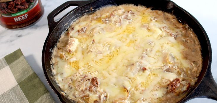 a cast iron skillet with cheese and meat in it next to a jar of beef seasoning