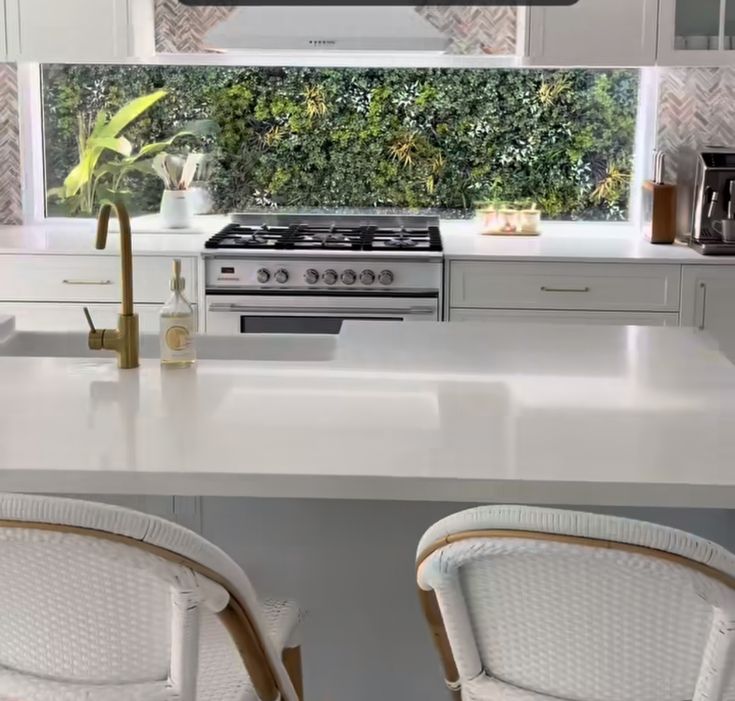 two white chairs sitting in front of a stove top oven next to a counter with a potted plant on it