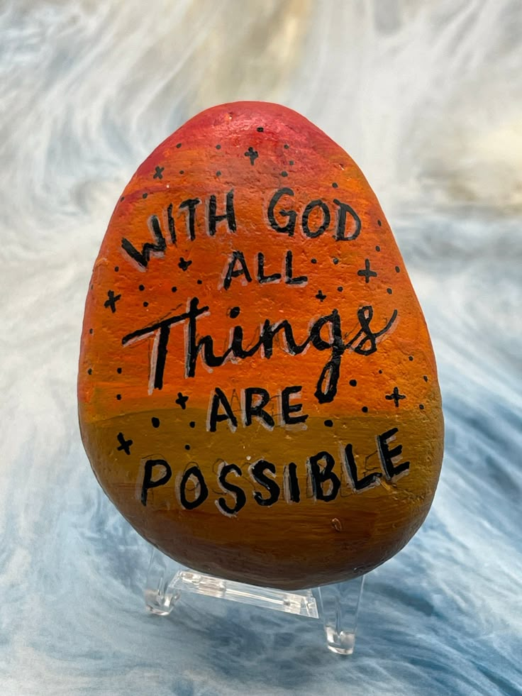 an orange painted rock with the words, with god all things are possible on it