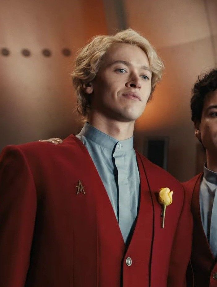 two men dressed in red suits and one is wearing a yellow rose on his lapel