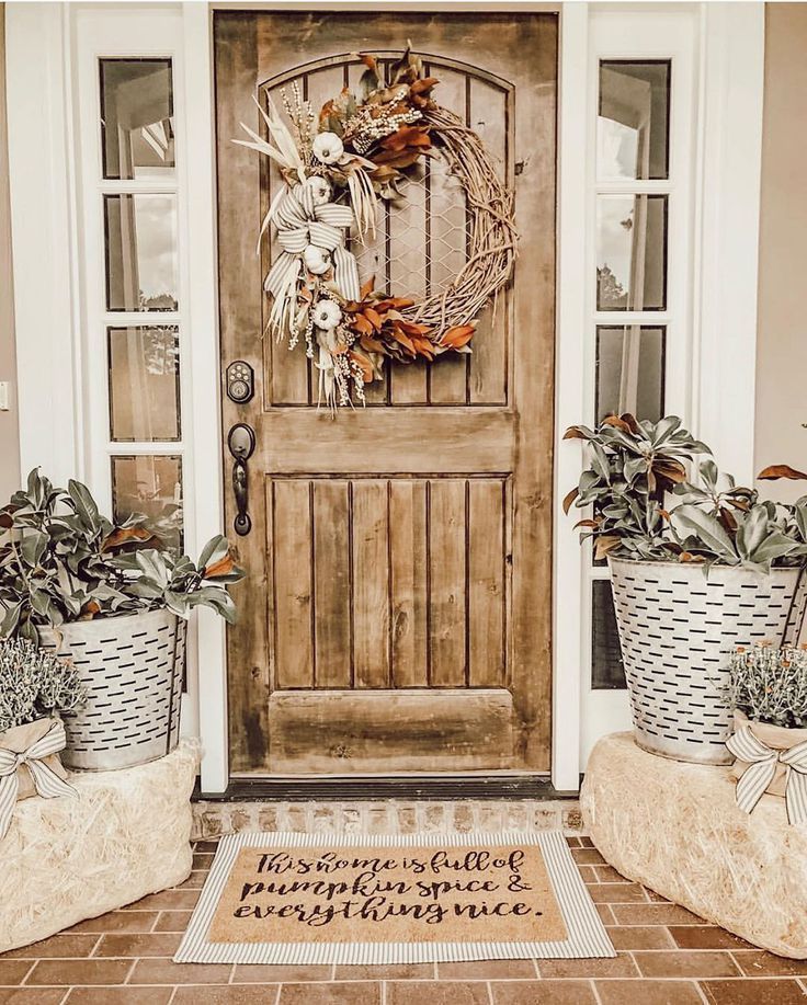 two planters are sitting in front of a wooden door with a wreath on it