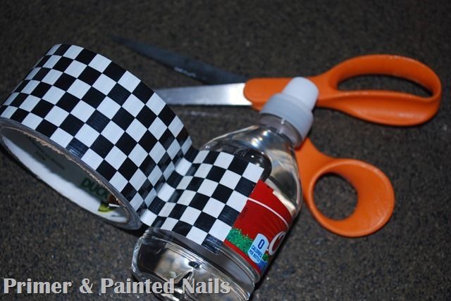 a pair of scissors and tape are sitting on the floor next to a bottle with a checkerboard design