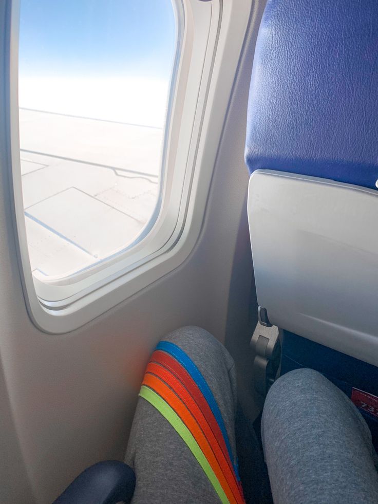 the view from inside an airplane looking at the wing and seat area with one person's feet propped up