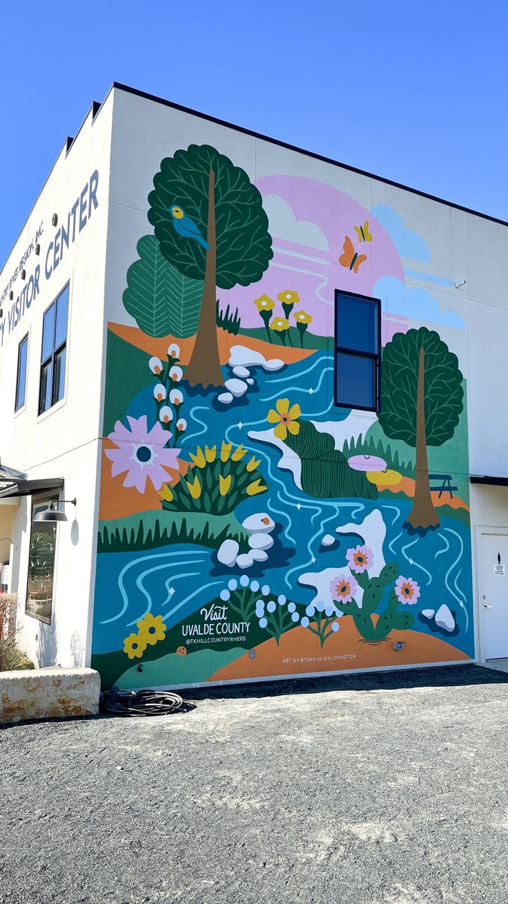 a large mural on the side of a building with trees and flowers painted on it