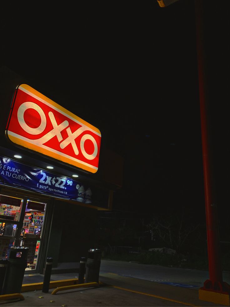 an ox convenience store at night with the sign lit up in red and white letters