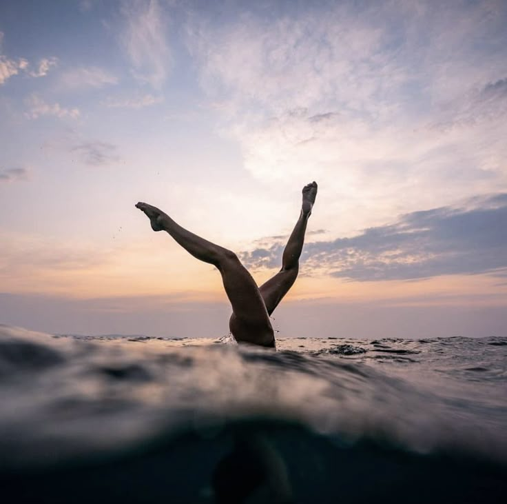 a man swimming in the ocean at sunset