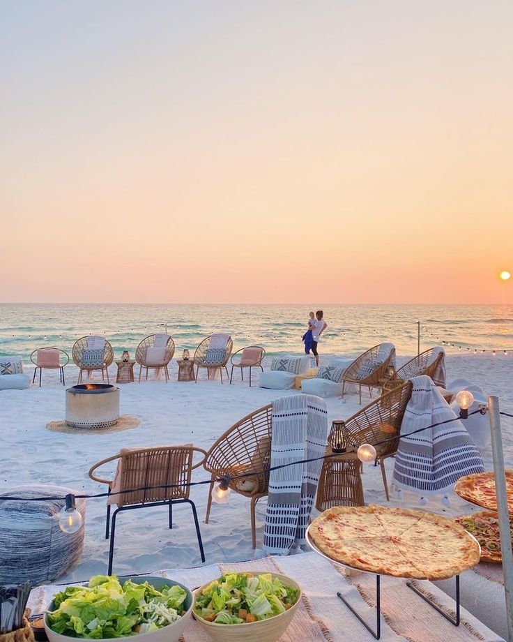 an outdoor dining area on the beach at sunset