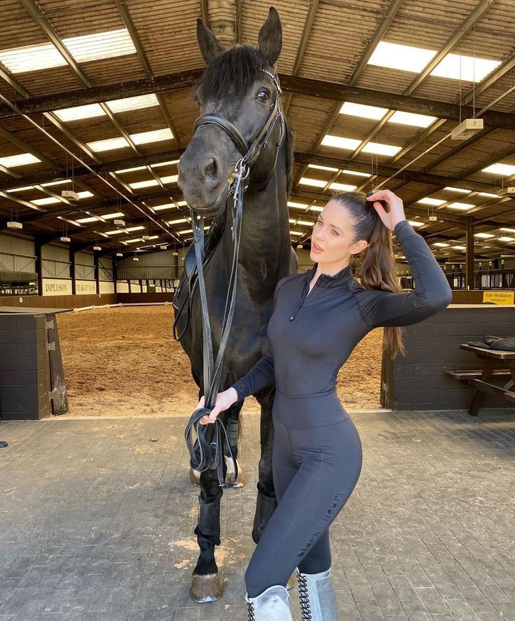 a woman standing next to a black horse