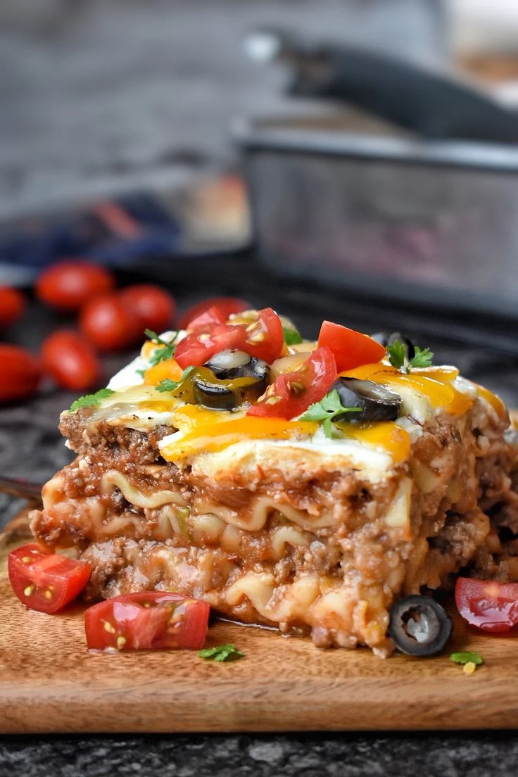 a wooden cutting board topped with lasagna casserole covered in cheese and toppings