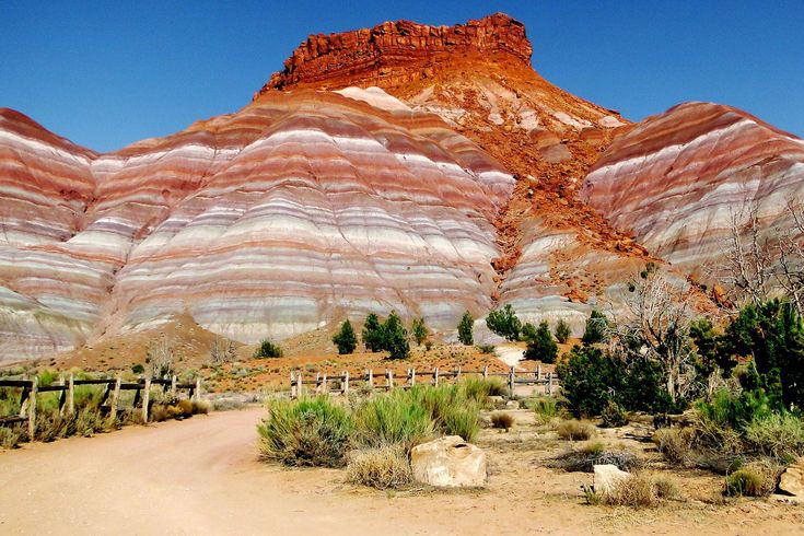 a dirt road in front of a mountain with red, white and blue stripes on it