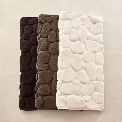 three bath mats in different colors and sizes on a wall with a white towel hanging from the side