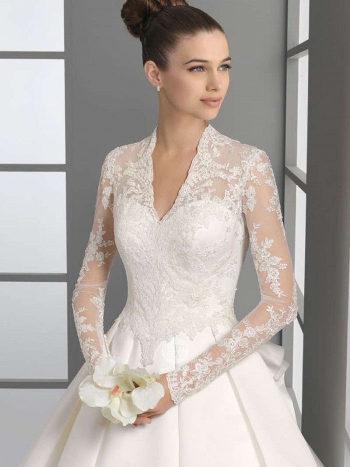 a woman in a white wedding dress with long sleeves and flowers on her hair is posing for the camera