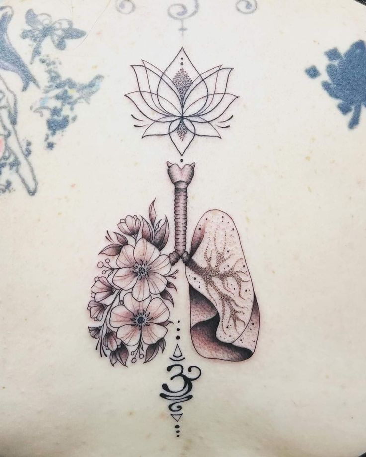 the back of a woman's stomach with tattoos on it and flowers in front