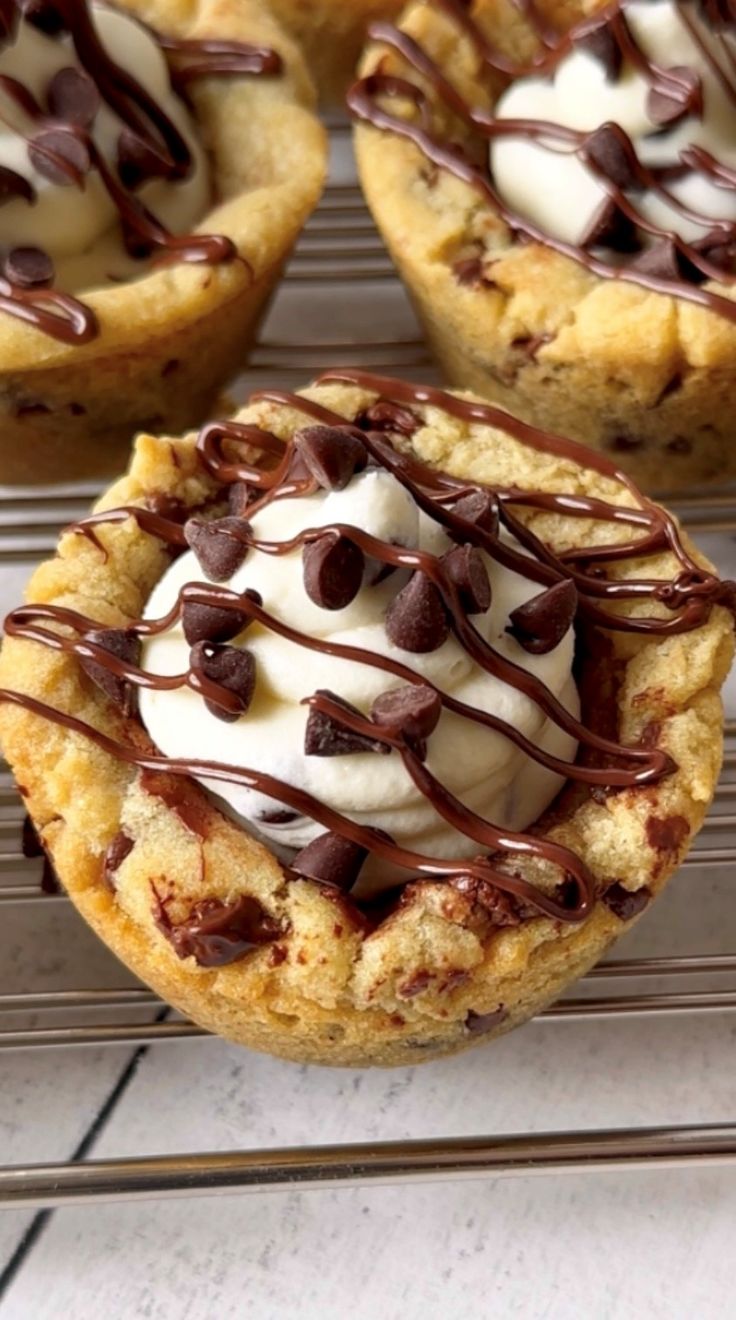 chocolate chip cookies with whipped cream and chocolate drizzled on top, sitting on a cooling rack