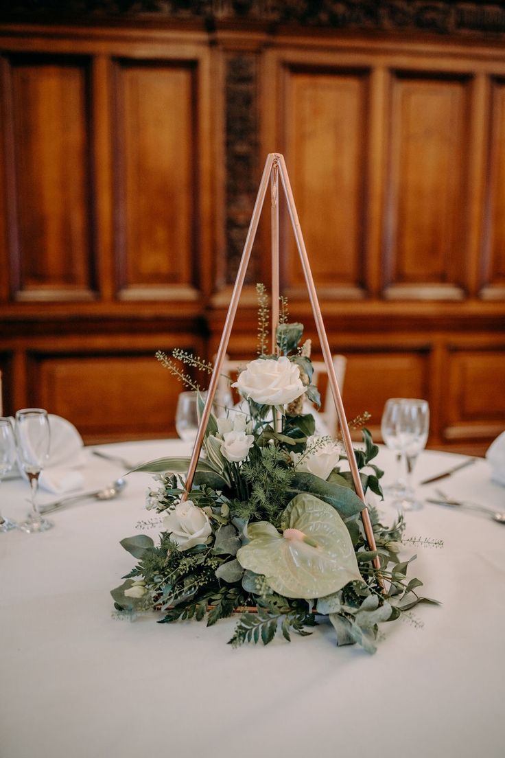 the table is set with white flowers and greenery for an elegant centerpiece or decoration