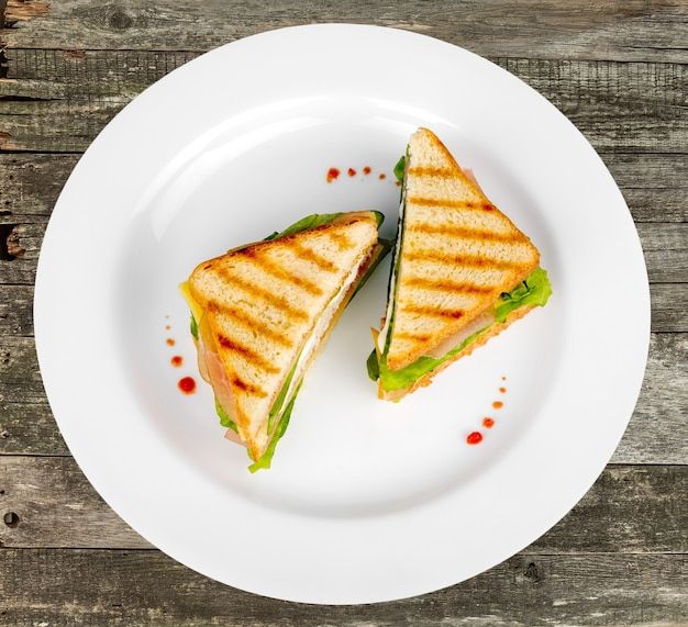 a white plate topped with a cut in half sandwich on top of a wooden table