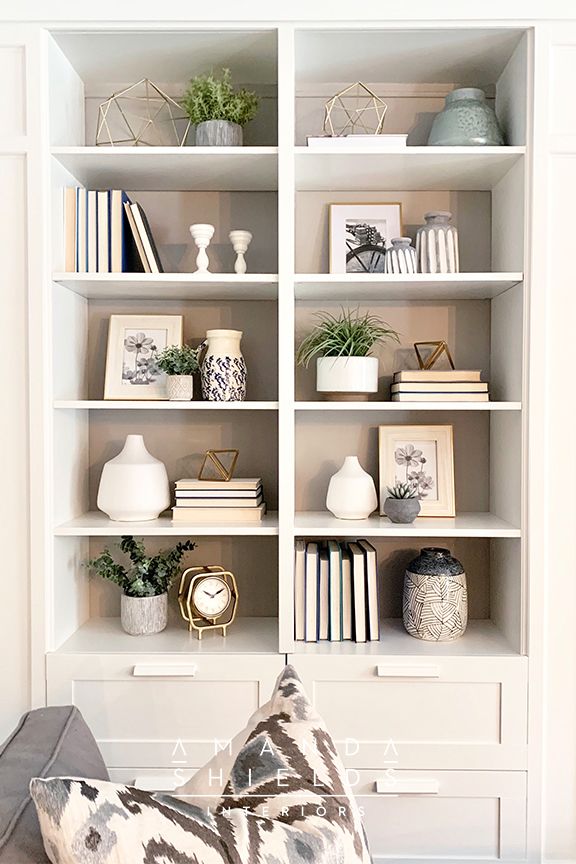 a white bookcase filled with lots of books and vases on top of it