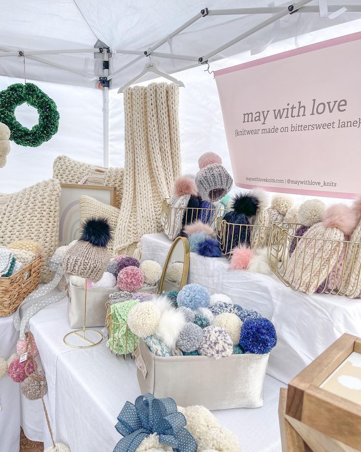 many knitted items are on display under a tent with a sign that says may with love